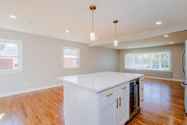 kitchen with white cabinets, a healthy amount of sunlight, decorative light fixtures, and light hardwood / wood-style floors