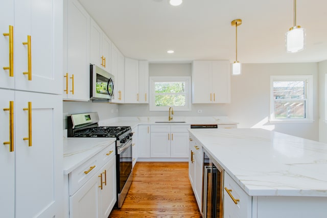 kitchen featuring white cabinets, plenty of natural light, hanging light fixtures, and appliances with stainless steel finishes