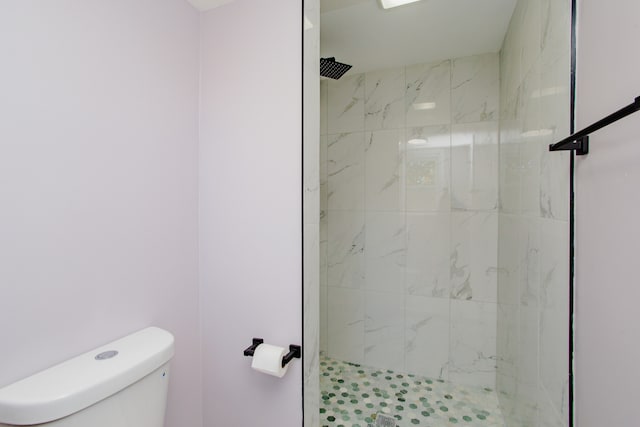 bathroom with a tile shower and toilet