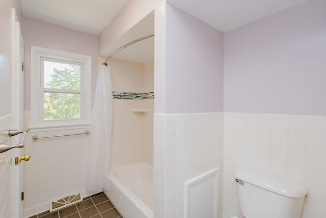 bathroom featuring tile patterned floors, shower / bathtub combination with curtain, toilet, and tile walls