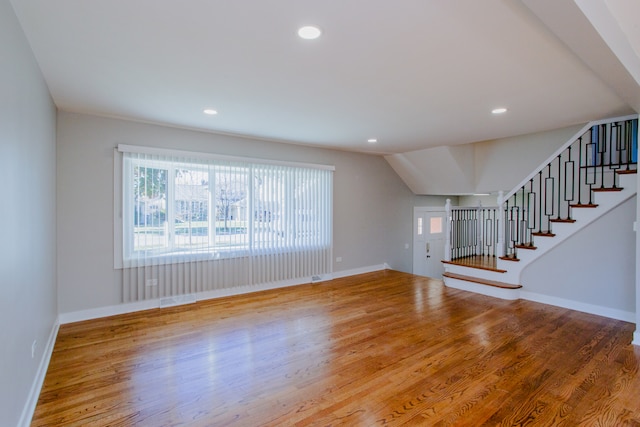 unfurnished living room with wood-type flooring and vaulted ceiling