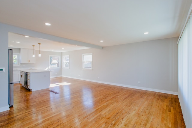 unfurnished living room featuring light hardwood / wood-style flooring, beverage cooler, and a healthy amount of sunlight