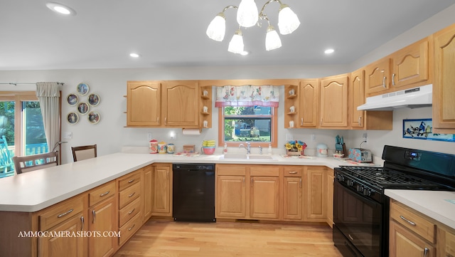 kitchen with sink, black appliances, hanging light fixtures, and plenty of natural light