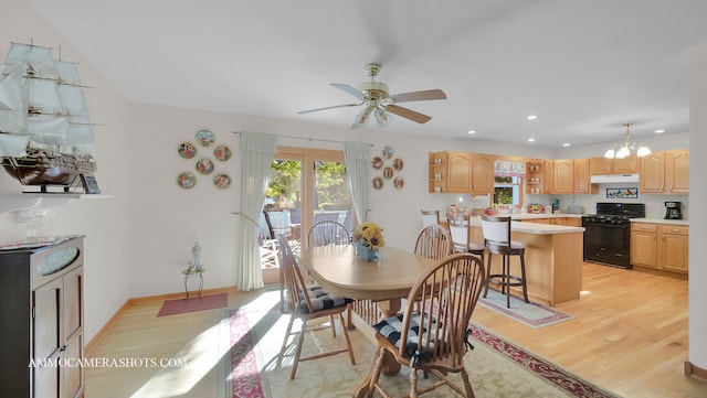 dining space featuring light wood-type flooring and ceiling fan with notable chandelier