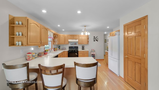 kitchen with a kitchen bar, kitchen peninsula, gas stove, and white refrigerator