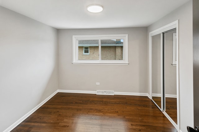 unfurnished bedroom with dark wood-type flooring and a closet