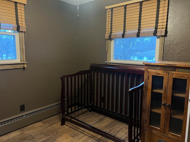 unfurnished bedroom featuring hardwood / wood-style flooring and baseboard heating