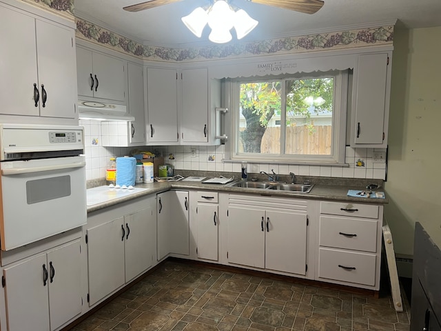 kitchen featuring white oven, white cabinetry, and sink