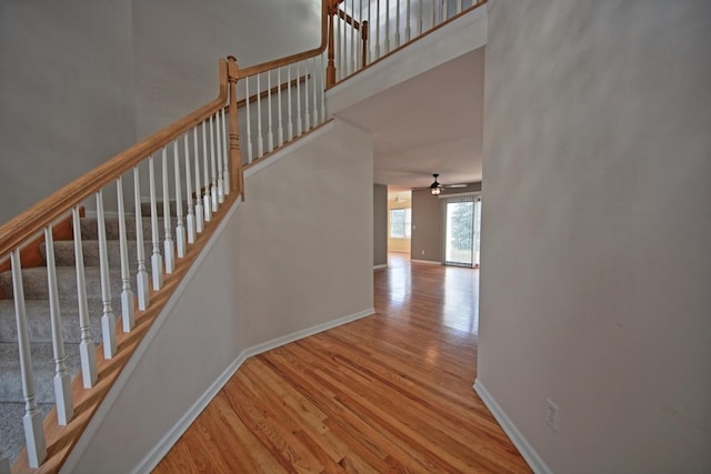 stairs with ceiling fan and hardwood / wood-style flooring