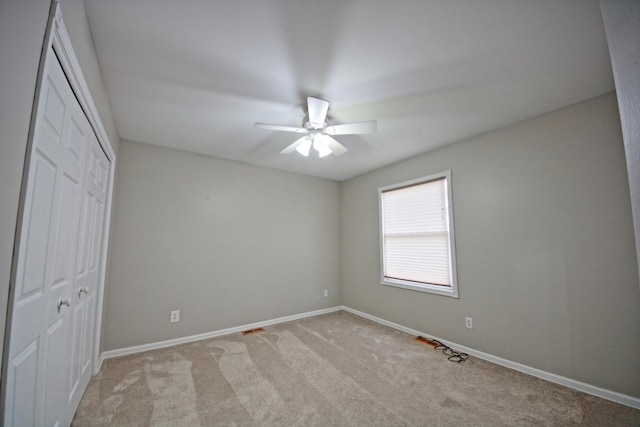 unfurnished bedroom with ceiling fan, a closet, and light carpet