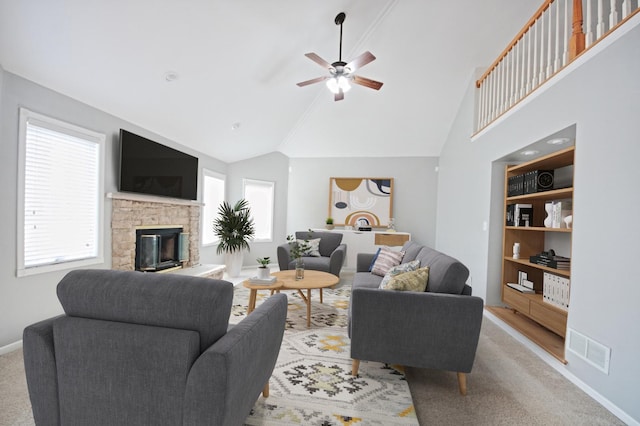 carpeted living room featuring a stone fireplace, ceiling fan, and high vaulted ceiling