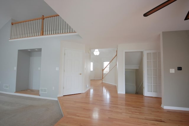 unfurnished room with a towering ceiling and light hardwood / wood-style floors