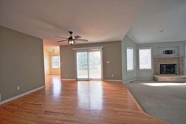 unfurnished living room featuring ceiling fan, light wood-type flooring, a fireplace, and lofted ceiling