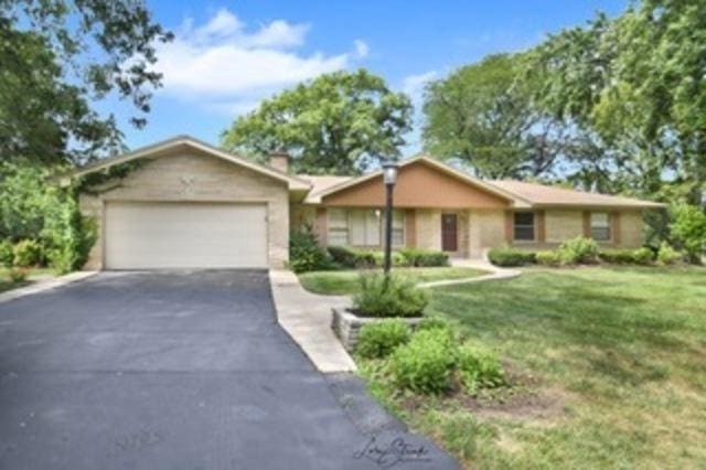 ranch-style home with a garage and a front lawn