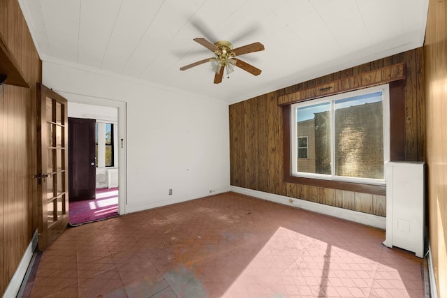 unfurnished room featuring ceiling fan, wooden walls, and crown molding