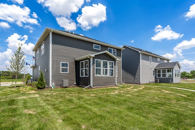 rear view of house with a lawn, central AC unit, and a sunroom