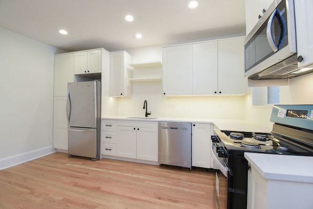 kitchen with white cabinets, sink, light wood-type flooring, and stainless steel appliances