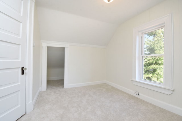 bonus room with light colored carpet and vaulted ceiling