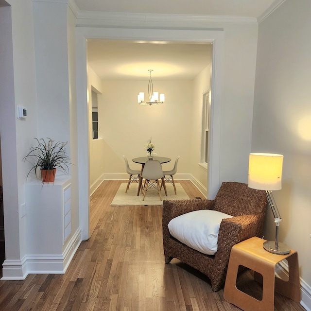 sitting room with hardwood / wood-style flooring, a notable chandelier, and ornamental molding