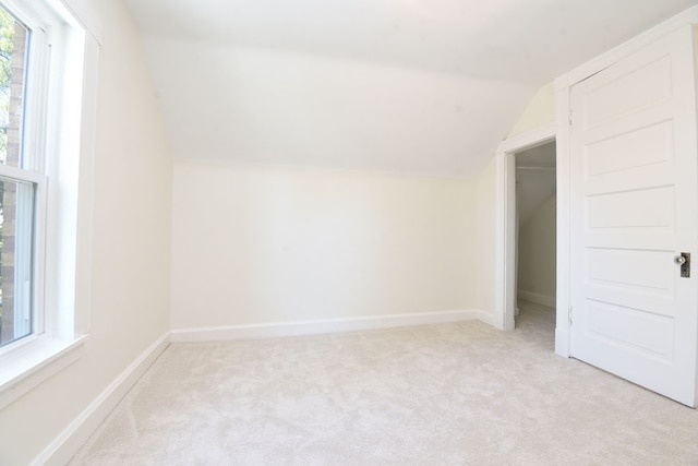 bonus room with lofted ceiling and light carpet