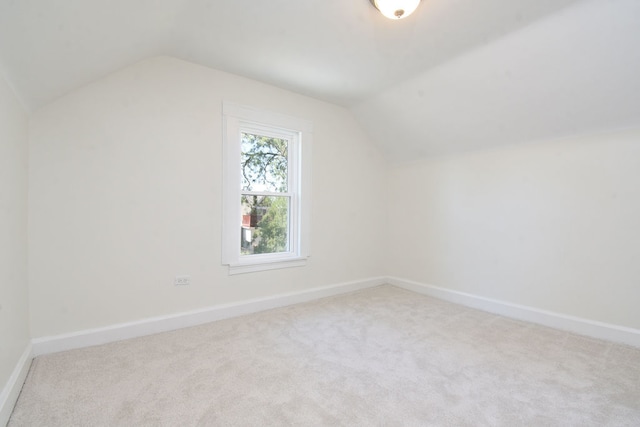 additional living space featuring lofted ceiling and light carpet