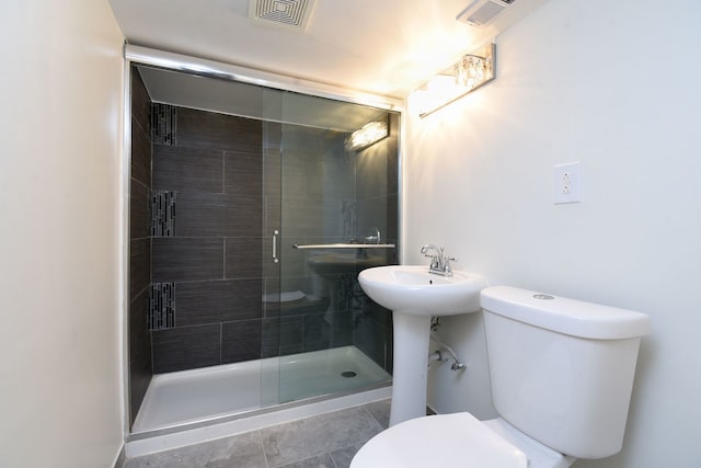 bathroom with tile patterned flooring, toilet, and a shower with shower door