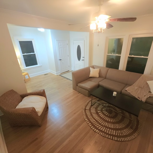 living room with ceiling fan, ornamental molding, and light wood-type flooring