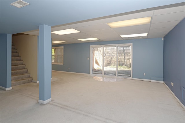 basement featuring a paneled ceiling and light colored carpet