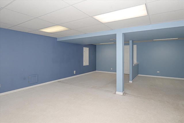 basement with a paneled ceiling and light carpet