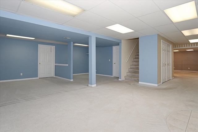 carpeted empty room featuring built in features and a drop ceiling