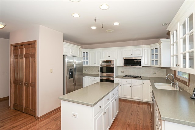 kitchen with dishwasher, a kitchen island, white cabinetry, and sink