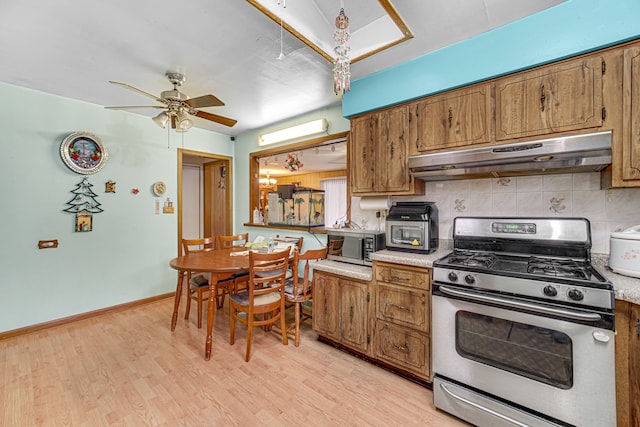 kitchen with light hardwood / wood-style floors, ceiling fan, decorative backsplash, and appliances with stainless steel finishes