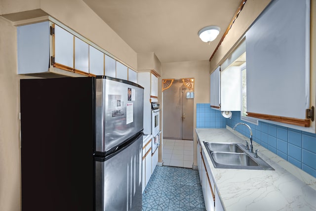 kitchen featuring white cabinetry, sink, and stainless steel refrigerator