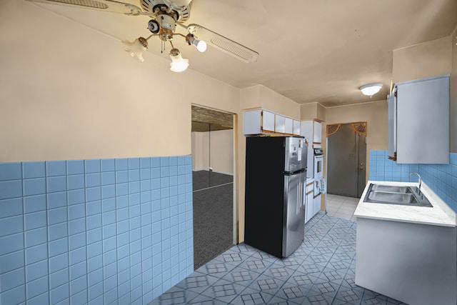 kitchen featuring tile walls, stainless steel fridge, light tile patterned floors, white cabinets, and ceiling fan