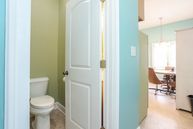 bathroom featuring an inviting chandelier and toilet