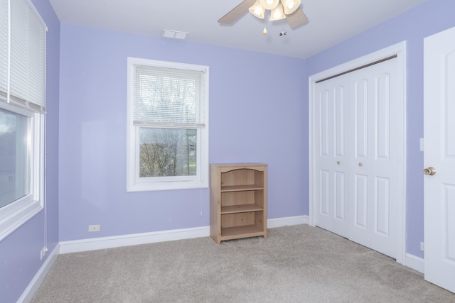 unfurnished bedroom featuring light carpet, a closet, and ceiling fan