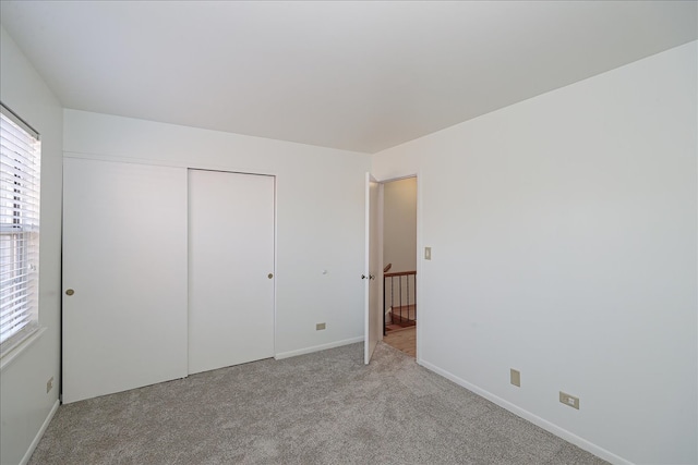 unfurnished bedroom featuring light carpet and a closet