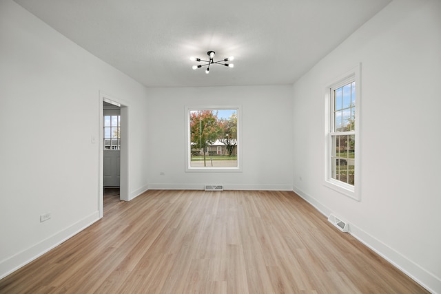 spare room featuring a textured ceiling, an inviting chandelier, and light hardwood / wood-style flooring