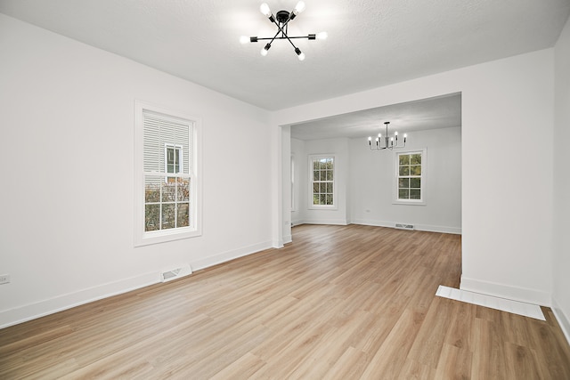 interior space with light wood-type flooring, a textured ceiling, and an inviting chandelier