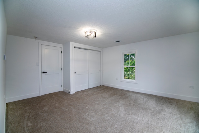 unfurnished bedroom featuring carpet, a textured ceiling, and a closet