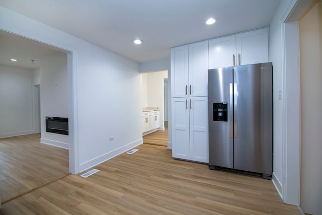 kitchen with white cabinets, stainless steel fridge, and light wood-type flooring