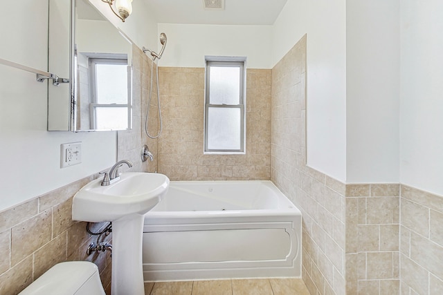 bathroom with toilet, tiled shower / bath combo, tile walls, and tile patterned floors