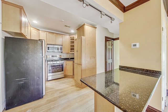 kitchen featuring stainless steel appliances, track lighting, kitchen peninsula, dark stone counters, and light hardwood / wood-style flooring