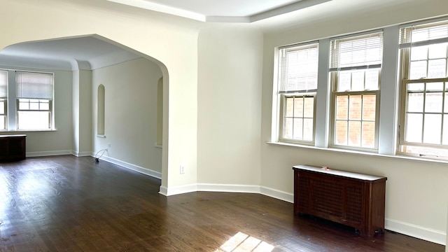 spare room featuring dark wood-type flooring and radiator