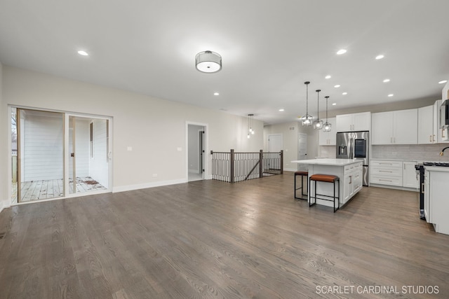 kitchen featuring a center island, white cabinets, hanging light fixtures, wood-type flooring, and stainless steel appliances