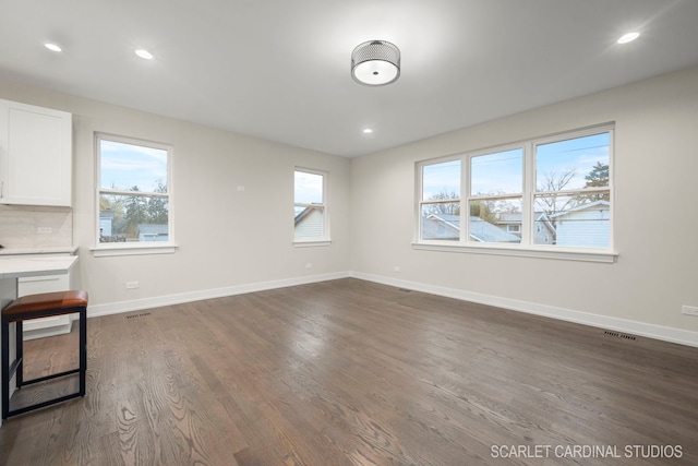 unfurnished living room featuring dark hardwood / wood-style flooring and a healthy amount of sunlight