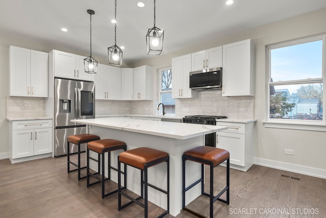 kitchen with plenty of natural light, white cabinets, stainless steel appliances, and a kitchen island