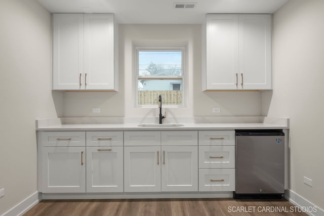 kitchen featuring white cabinetry, stainless steel refrigerator, and sink