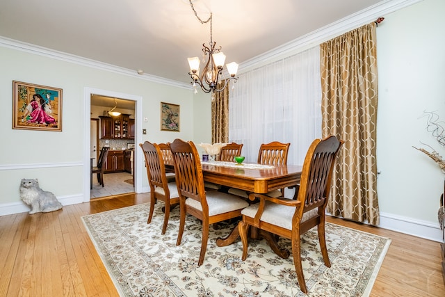 dining room with crown molding, light hardwood / wood-style flooring, and an inviting chandelier