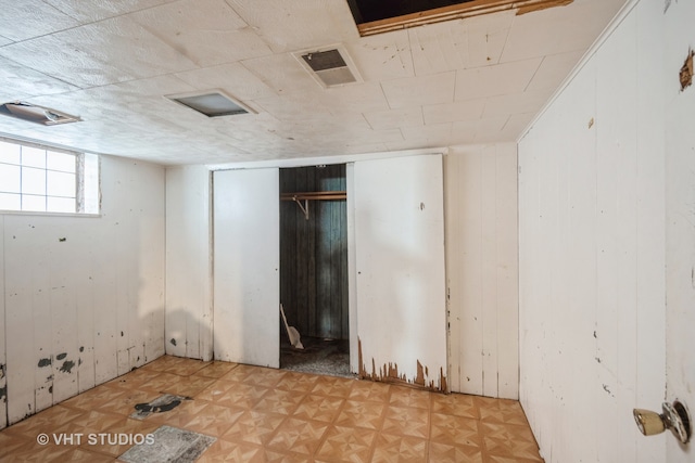 spare room with light parquet floors and wooden walls